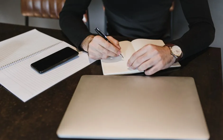 Carnet ouvert et ordinateur portable sur une table : préparer un message